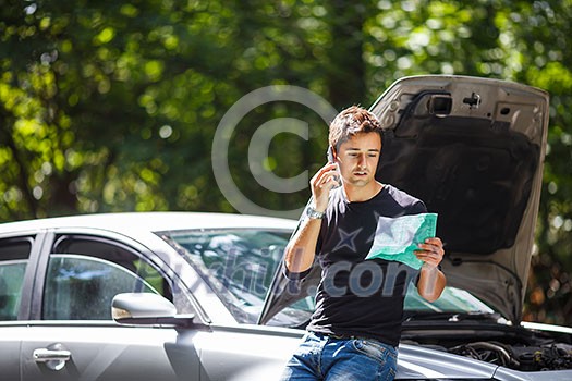 Handsome young man calling for assistance with his car broken down by the roadside