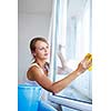 Pretty, young woman doing house work - washing windows (shallow DOF; color toned image)