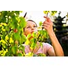 Pretty female gardener taking care of her lovely garden on a spring day - cutting branches, double digging/loosening the soil with a spade