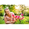 Pretty female gardener taking care of her lovely garden on a spring day - admiring the tulips