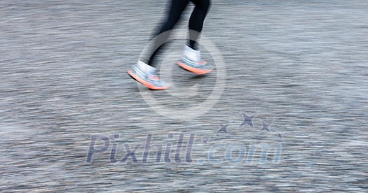 Motion blurred runner's feet in a city environment (panning technique used -> motion blurred image; color toned image)