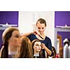 Pretty female hairdresser/haidressing apprentice/student training on an apprentice head