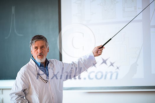 Senior chemistry professor giving a lecture in front of classroom full of students (shallow DOF; color toned image)