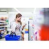 Beautiful young woman shopping in a grocery store/supermarket (color toned image)