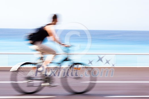 Great way to get around in a city -Motion blurred cyclist going fast on a city bike lane, by the sea shore