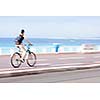 Great way to get around in a city -Motion blurred cyclist going fast on a city bike lane, by the sea shore