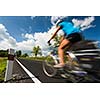Female cyclist biking on a country road on a lovely sunny day (motion blurred image with copy space)