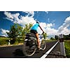 Female cyclist biking on a country road on a lovely sunny day (motion blurred image with copy space)