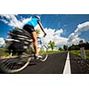 Female cyclist biking on a country road on a lovely sunny day (motion blurred image with copy space)