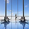 Image of woman in airport looking at taking off airplane