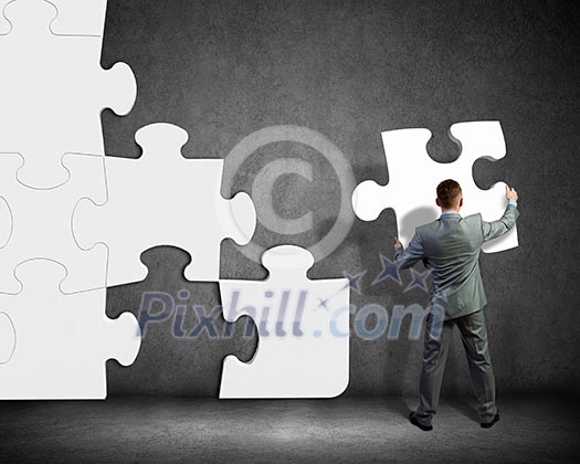 Image of businessman compiling macro white puzzle. Building business