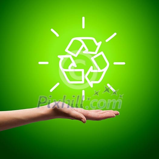 Recycling symbol in human hand against green background Recycling symbol in human hand against green background