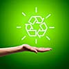 Recycling symbol in human hand against green background