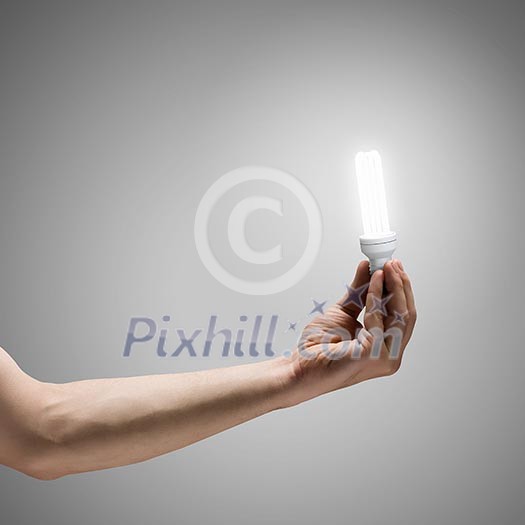 Close up image of human hand holding electrical bulb Close up image of human hand holding electrical bulb