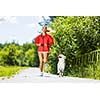 Young attractive sport girl running with dog in park