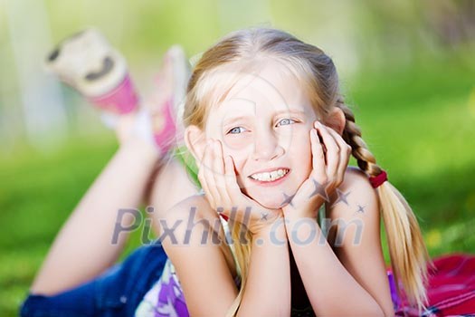 Image of little cute girl lying on grass in park