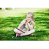 Image of little cute girl sitting on grass in park