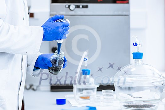 Hands of a researcher carrying out scientific research experiment in a lab (shallow DOF; color toned image)