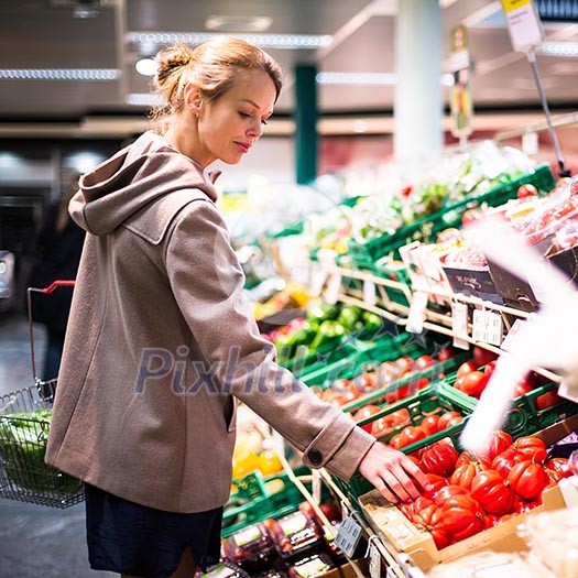 Beautiful young woman shopping for fruits and vegetables in produce department of a grocery store/supermarket