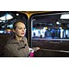 Pretty, young woman on a streetcar/tramway, during her evening commute home from work (color toned image; shallow DOF)