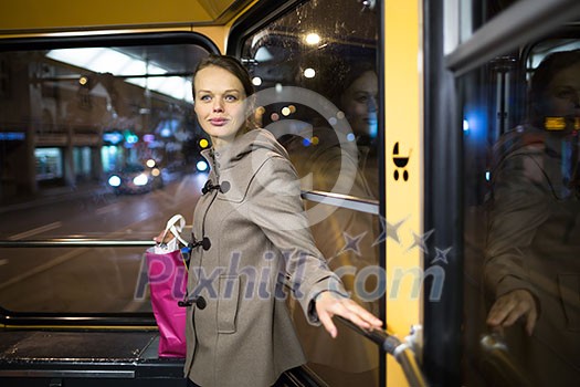 Pretty, young woman on a streetcar/tramway, during her evening commute home from work (color toned image; shallow DOF)