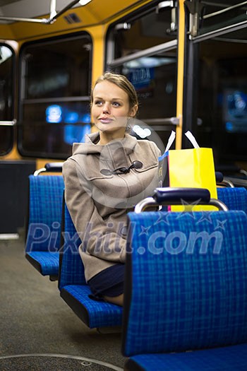 Pretty, young woman on a streetcar/tramway, during her evening commute home from work (color toned image; shallow DOF)