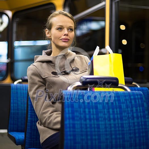 Pretty, young woman on a streetcar/tramway, during her evening commute home from work (color toned image; shallow DOF)