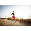 Caucasian young man running on a seacost path on a lovely summer evening, training for marathon (motion blurred image)