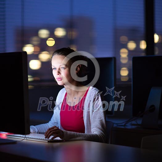 Pretty, young female college student using a desktop computer/pc in a college library (shallow DOF; color toned image)