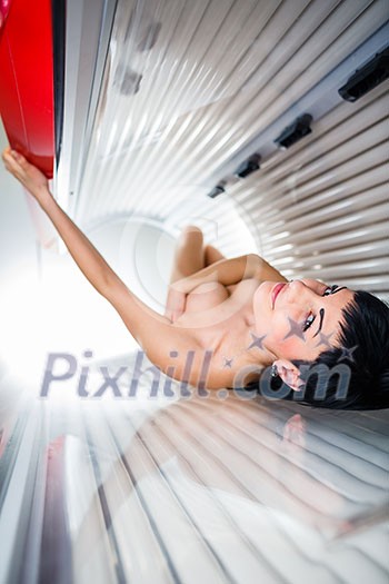 Pretty young woman tanning her skin in a modern solarium