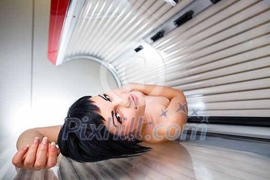 Pretty young woman tanning her skin in a modern solarium