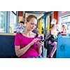 Pretty, young woman on a streetcar/tramway, during her commute to work/school (color toned image; shallow DOF)