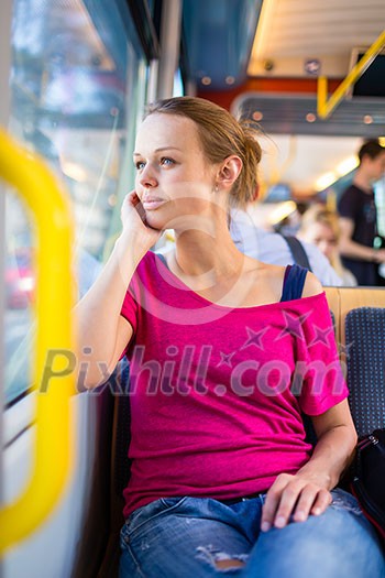Pretty, young woman on a streetcar/tramway, during her commute from work/school (color toned image; shallow DOF)