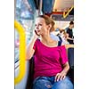 Pretty, young woman on a streetcar/tramway, during her commute from work/school (color toned image; shallow DOF)