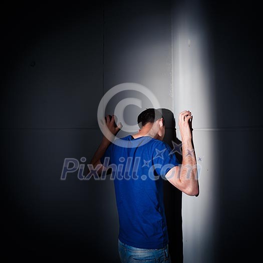 Young man suffering from a severe depression, anxiety (very harsh lighting is used on this shot to underline/convey the gloomy mood of the scene)