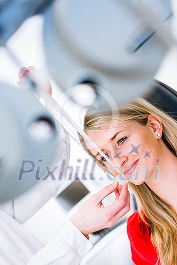 Optometry concept - pretty young woman having her eyes examined by an eye doctor (color toned image; shallow DOF)