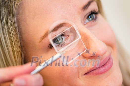 Optometry concept - pretty young woman having her eyes examined by an eye doctor (color toned image; shallow DOF)