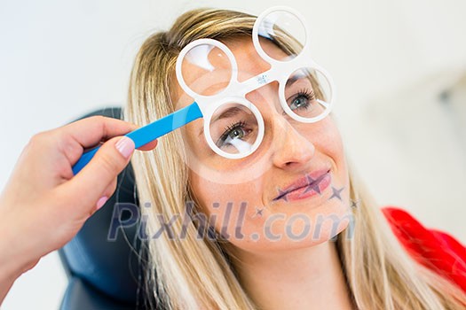 Optometry concept - pretty young woman having her eyes examined by an eye doctor (color toned image; shallow DOF)