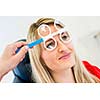 Optometry concept - pretty young woman having her eyes examined by an eye doctor (color toned image; shallow DOF)