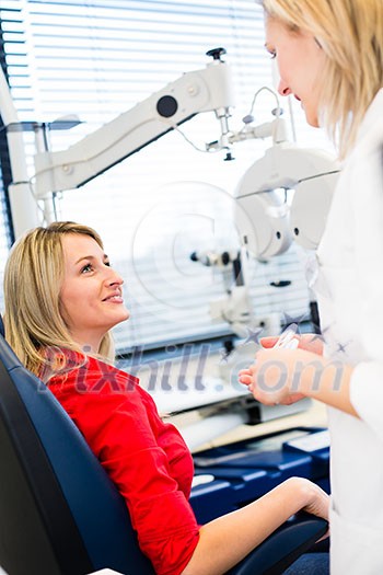 Optometry concept - pretty young woman having her eyes examined by an eye doctor (color toned image; shallow DOF)