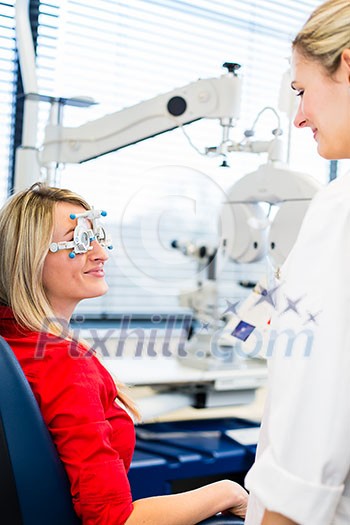 Optometry concept - pretty young woman having her eyes examined by an eye doctor (color toned image; shallow DOF) Optometry concept - pretty young woman having her eyes examined by an eye doctor (color toned image; shallow DOF)