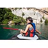 Pretty, young woman on a canoe on a lake, paddling, enjoying a lovely summer day