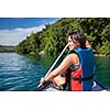 Pretty, young woman on a canoe on a lake, paddling, enjoying a lovely summer day