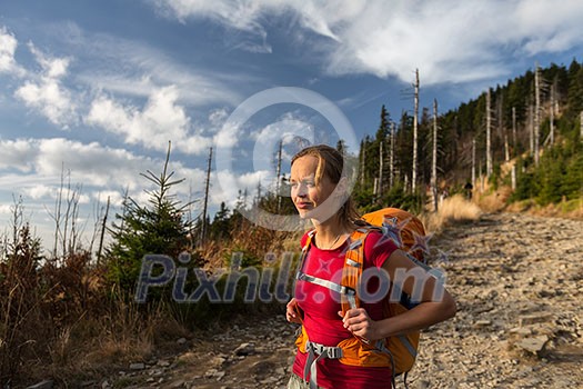 Pretty, female hiker going downhill in warm evening light Pretty, female hiker going downhill in warm evening light