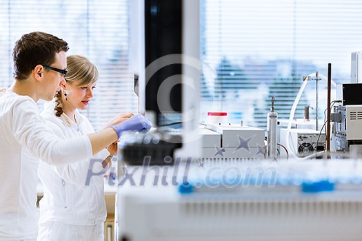Two young researchers carrying out experiments in a lab (shallow DOF; color toned image) Two young researchers carrying out experiments in a lab (shallow DOF; color toned image)