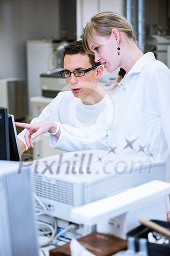 Two young researchers carrying out experiments in a lab (shallow DOF; color toned image)