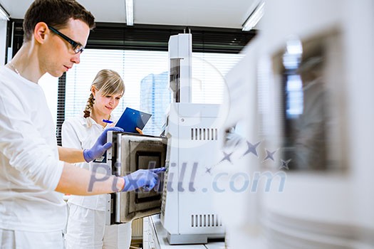 Two young researchers carrying out experiments in a lab (shallow DOF; color toned image)