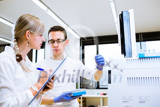 Two young researchers carrying out experiments in a lab (shallow DOF; color toned image)