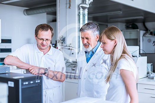 Team of researchers carrying out experiments in a lab (shallow DOF; color toned image)