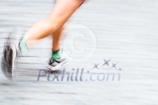 Motion blurred runner's feet in a city environment - running marathon (panning technique used -> motion blurred image; color toned image)